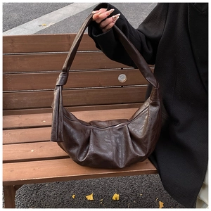 Detail of vintage dark brown crescent bag showing pleated faux leather and knot strap