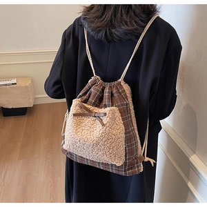 Gros plan d'un sac à dos écossais marron avec poche en polaire beige et nœud déco
