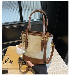 Détail du sac seau en toile beige avec garniture en cuir marron et breloque mouton