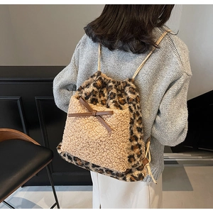Détail d'un sac à dos léopard en fausse fourrure avec poche sherpa et nœud sur modèle