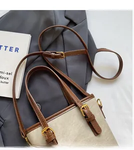Détail du sac seau en toile avec garniture en cuir marron et bandoulière réglable