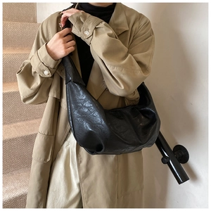 Detail of black crescent hobo bag with vintage pleated texture on neutral background