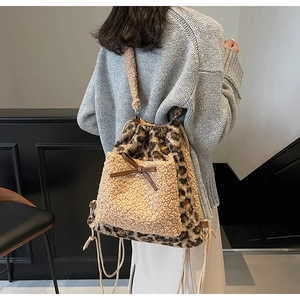 Détail du sac à dos léopard en peluche avec poche beige et nœud en cuir décoratif