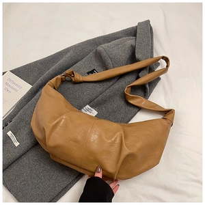Close-up of brown pleated crescent bag with knotted strap on a wool coat