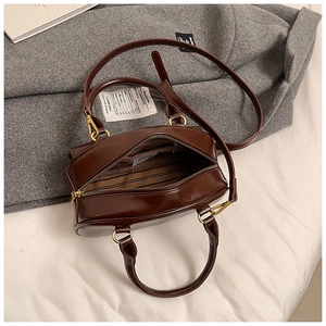 Detail of dark brown leather bowling bag with striped lining and inner zipper pocket