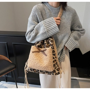 Détail du sac seau en peluche léopard avec poche en polaire et nœud en cuir marron