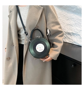 Fashionable dark green record-shaped round bag worn by model in a stylish interior setting