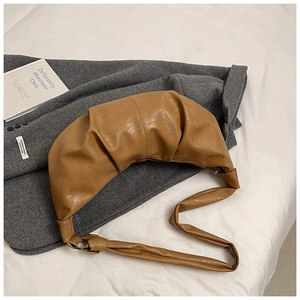 Detail of soft dark brown leather croissant bag with stylish pleats and metallic strap ring