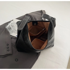 Detail view of large black tote bag interior showing zipper pocket and brown lining