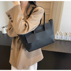 Détail du sac cabas en cuir noir grainé montrant la texture et la bandoulière