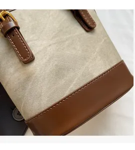 Détail du canvas et cuir marron avec logo doré sur le sac seau au style vintage