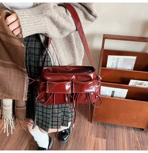 Detail of dark red vintage shoulder bag featuring glossy finish and double front pockets