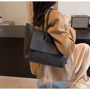 Détail du sac cabas en cuir grainé noir avec rabat asymétrique porté à l'épaule