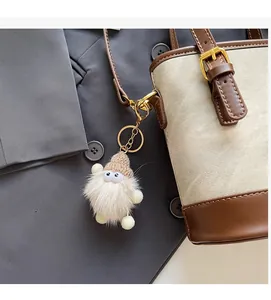 Gros plan d'un gri-gri monstre en peluche avec bonnet sur un sac seau en cuir beige