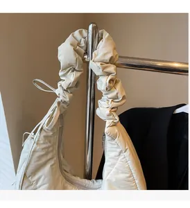 Detail of quilted nylon bag showing ruched handle texture and smooth zip closure
