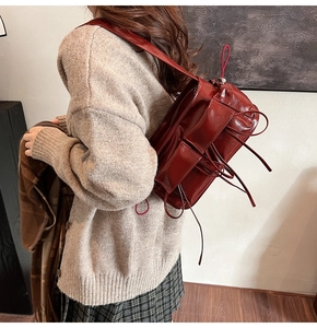 Close-up of deep red patent leather shoulder bag with decorative ribbons for women