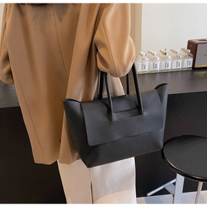 Sac fourre-tout chic en cuir noir porté avec un blazer kaki pour un style de bureau moderne