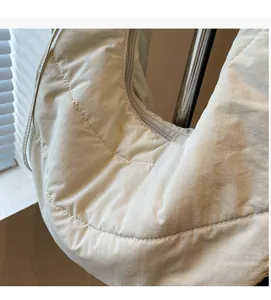Detailed macro view of cream quilted nylon hobo bag featuring soft pleated texture and zipper