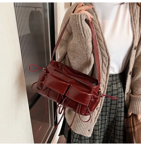 Detailed view of a dark red bow shoulder bag with glossy texture and double front pockets
