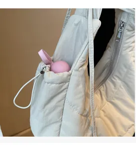 Detail of quilted puffer bag side pocket with drawstring and pink spherical ornament
