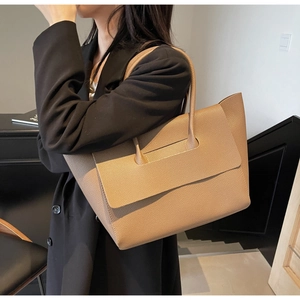 Détail du grand sac cabas en cuir grainé abricot porté par un mannequin dans une pièce