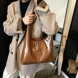Brown vintage large capacity shoulder bag with drawstring bow detail worn by model