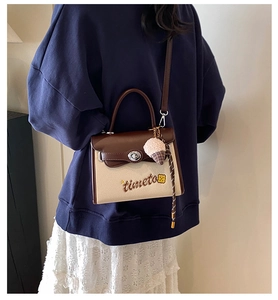 Detail of canvas crossbody bag with leather trim and pink plush ice cream charm