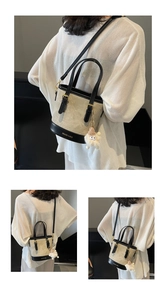 Détail du sac seau en toile beige avec finitions en cuir noir et breloque monstre peluche