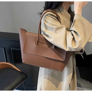 Gros plan du sac cabas en cuir marron grainé avec poignée ronde et boucle de rabat