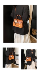Detail of a brown leather shoulder bag with a metal magnetic clasp and pompom charm