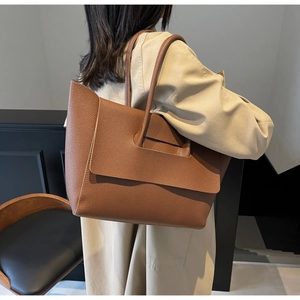 Détail de la texture cuir grainé du sac cabas marron caramel porté par un mannequin