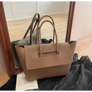Détail du sac cabas en cuir grainé avec une silhouette d'aile au design unique