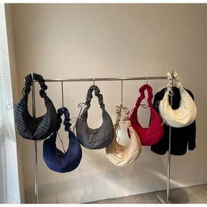 Selection of colorful quilted dumpling bags with ruffled handles on a display stand