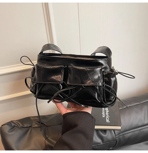 Detailed macro view of black glossy leather handbag with double pockets and lace-up design