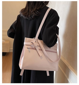 Detail of glossy pink tote bag with zip pocket and knot handle shown on model back