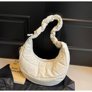 Detail of ivory quilted dumpling bag with stylish scrunchie shoulder strap and puff design