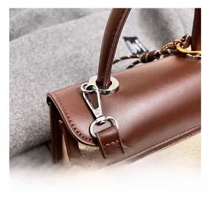 Detail of silver metal hook and D-ring on a brown leather and canvas crossbody bag