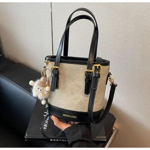 Détail du sac seau en toile avec base en cuir noir et breloque monstre en peluche