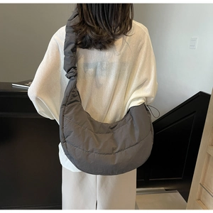 Detail view of large quilted crossbody bag with pleated strap on shoulder