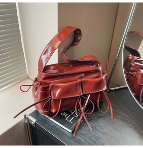 Close-up of shiny dark red shoulder bag with functional pockets and long drawstrings
