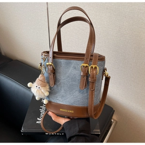 Détail d'un sac seau en denim et cuir avec breloque en peluche sur magazine