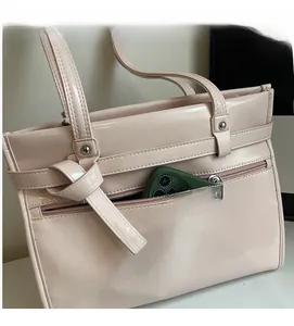 Detail view of large beige tote bag featuring a practical front zipper pocket and knotted strap