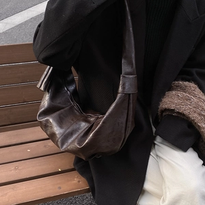 Retro dark brown crescent shoulder bag with vintage leather texture on a model