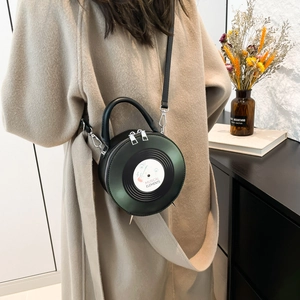 Retro vinyl record-shaped crossbody bag in dark green leather shown on model outfit