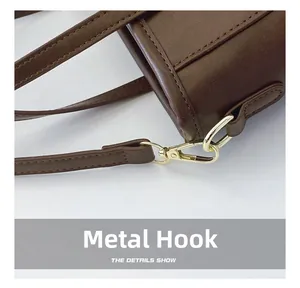 Macro shot of gold-tone hardware hook and stitching on coffee brown leather bag