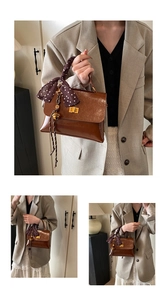 Detail view of brown glossy shoulder bag with silk scarf handle and gold twist lock
