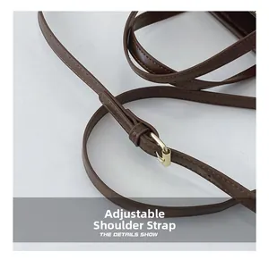 Detail of dark brown leather adjustable shoulder strap with gold metal buckle and stitching