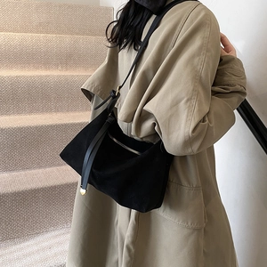 Classic black suede crossbody bag with gold zippers worn with a long trench coat