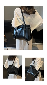 Detailed view of large black faux leather tote bag showing slim belt buckle decoration