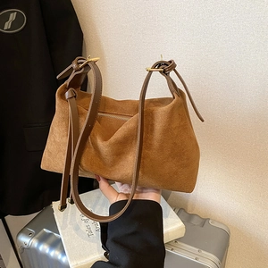Brown suede tote bag with leather straps and gold buckle in a casual lifestyle setting
